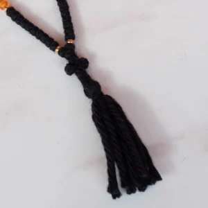 Detail of the tassel of 50 knots black wool brojanica with orange and gold beads